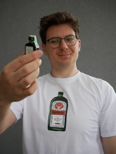 Model prezentuje białą koszulkę "DARK GREEN" z nadrukiem z przodu