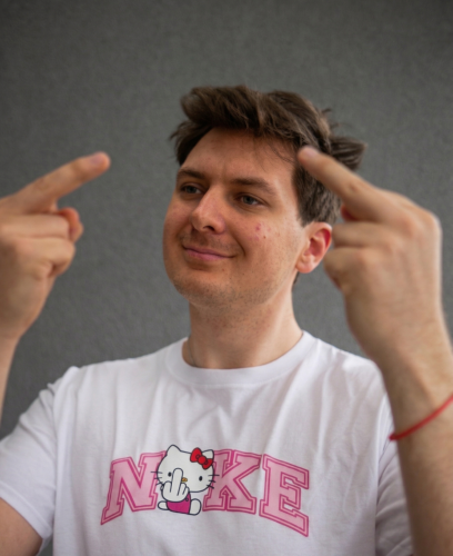 Model prezentuje białą koszulkę "F*CK KITTY - RÓŻOWA" z nadrukiem z przodu